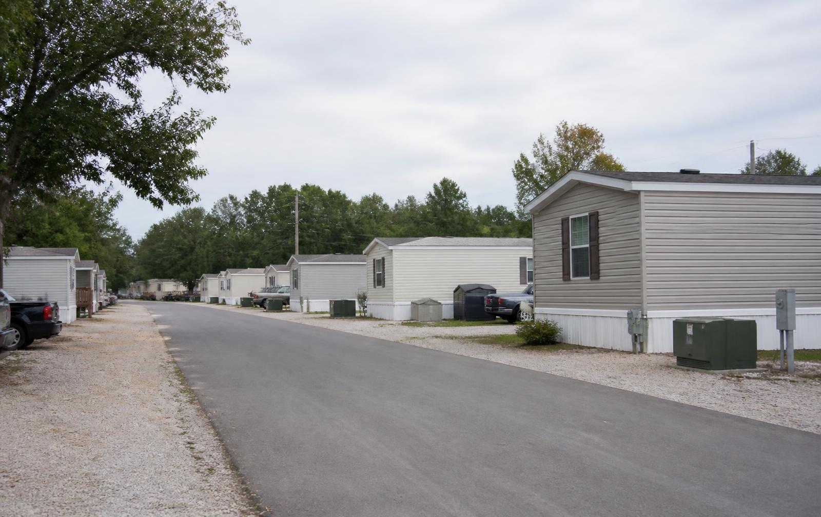 Interior street of a manufactured housing community with older single-wide homes and utility pedestals