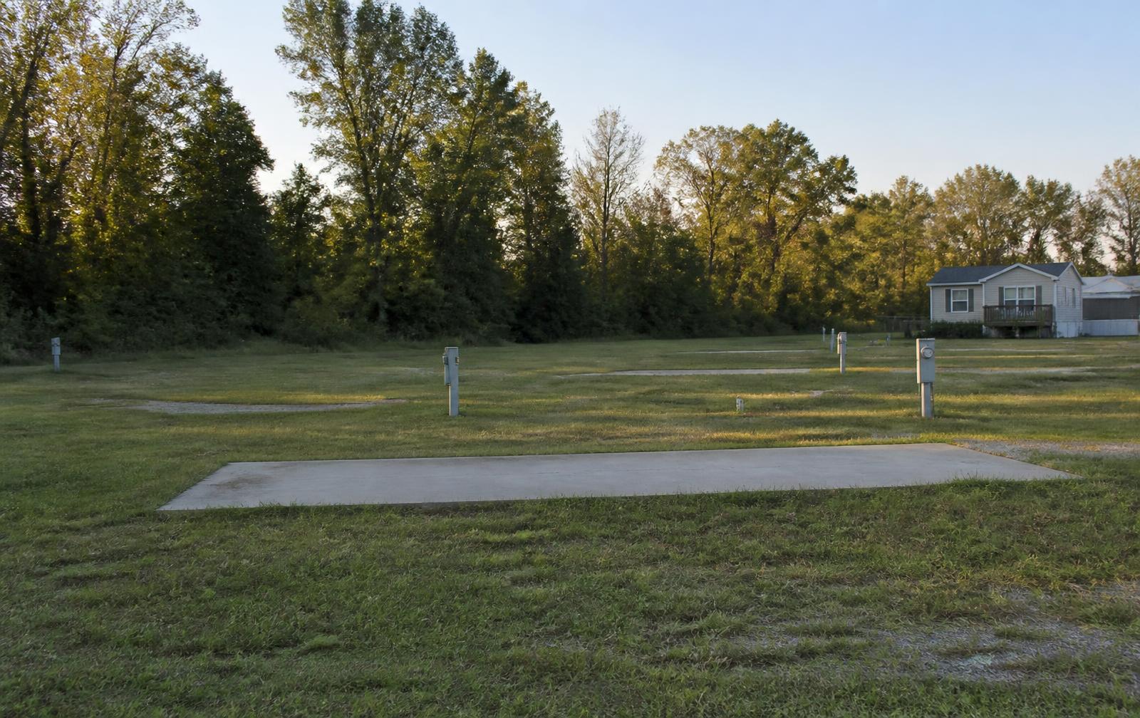 Vacant concrete pads with utility risers at the edge of a mobile home park